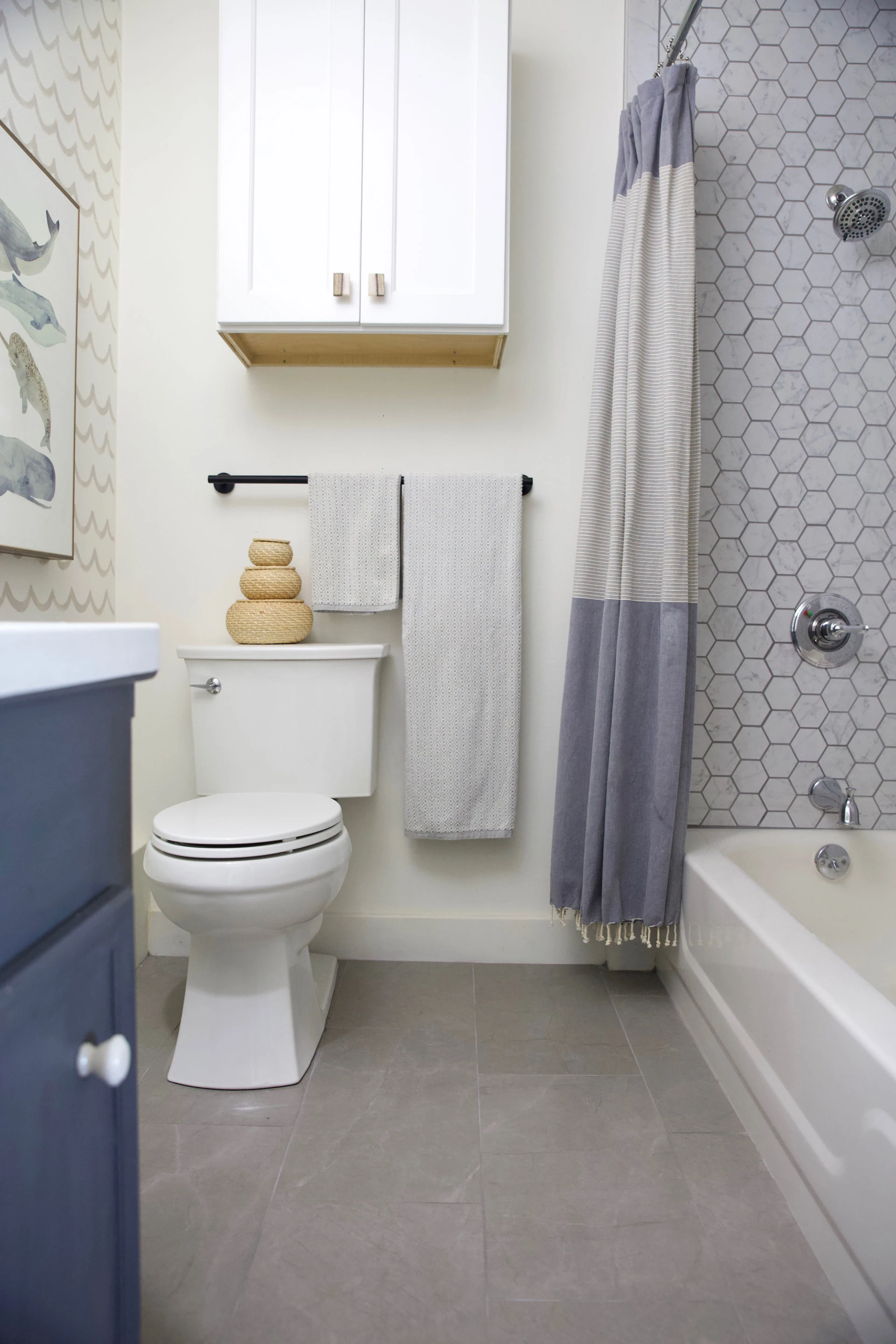 Atlas Concorde USA Eon Corinthian Gray tile on the bathroom floor and Eon Carrara Honeycomb Mosaic tile used as the shower wall.