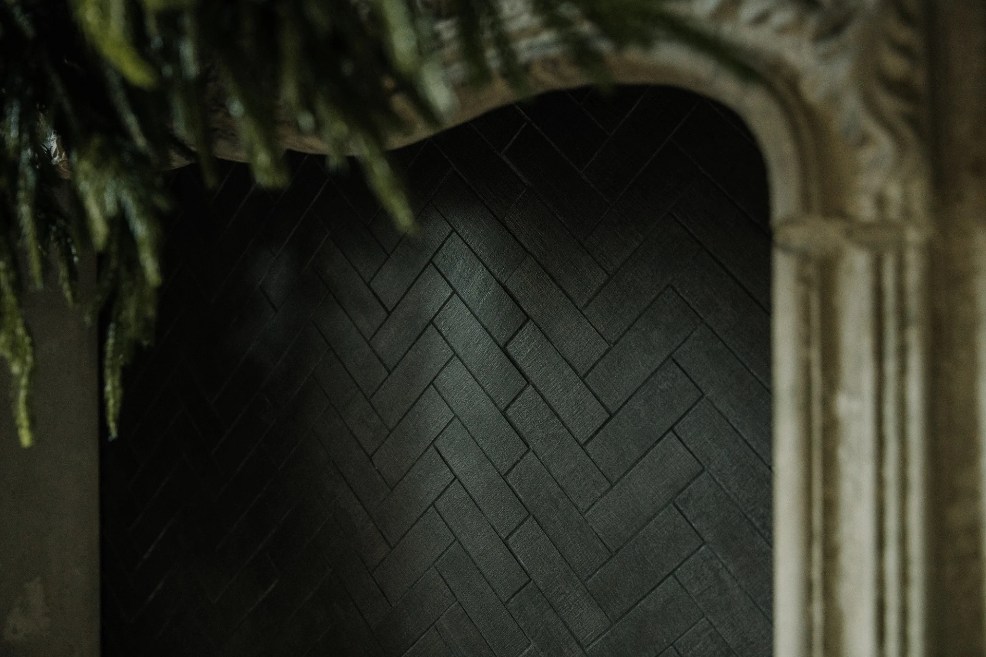 Dark olive wall with modern Victorian fireplace and black fabric-look porcelain tile in the faux fireplace.